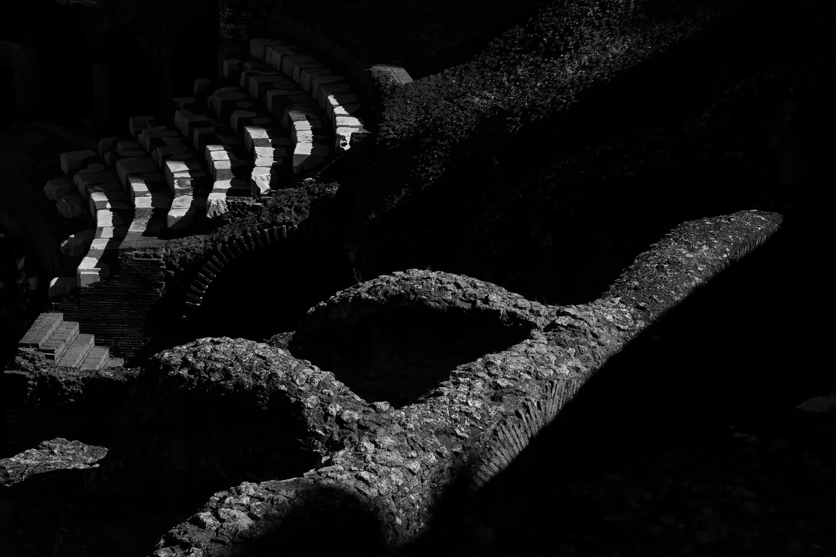 Roman arches in deep shadow, light caught only along their tops.