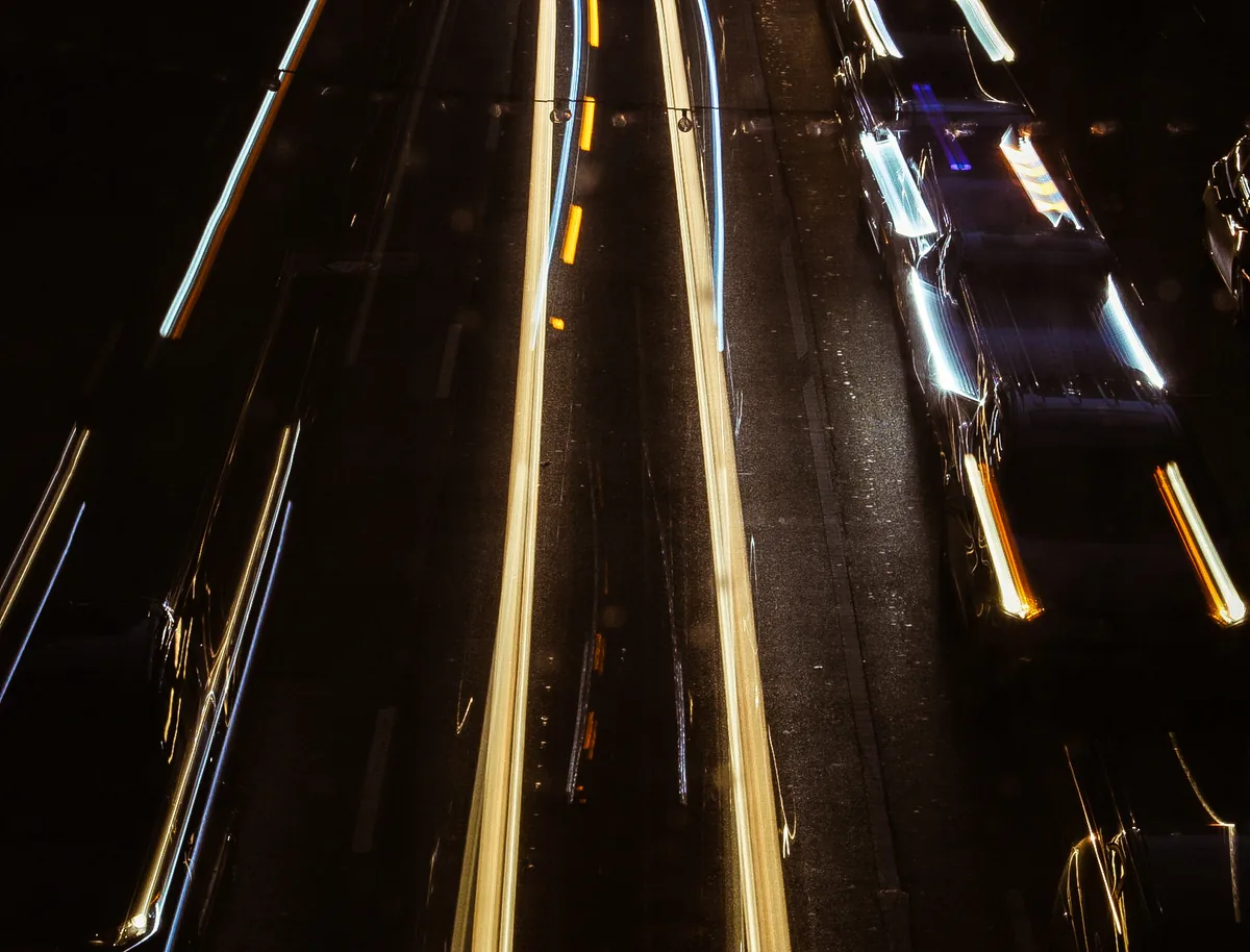 Traffic reduced to streaks of light on a dark highway in a long exposure.