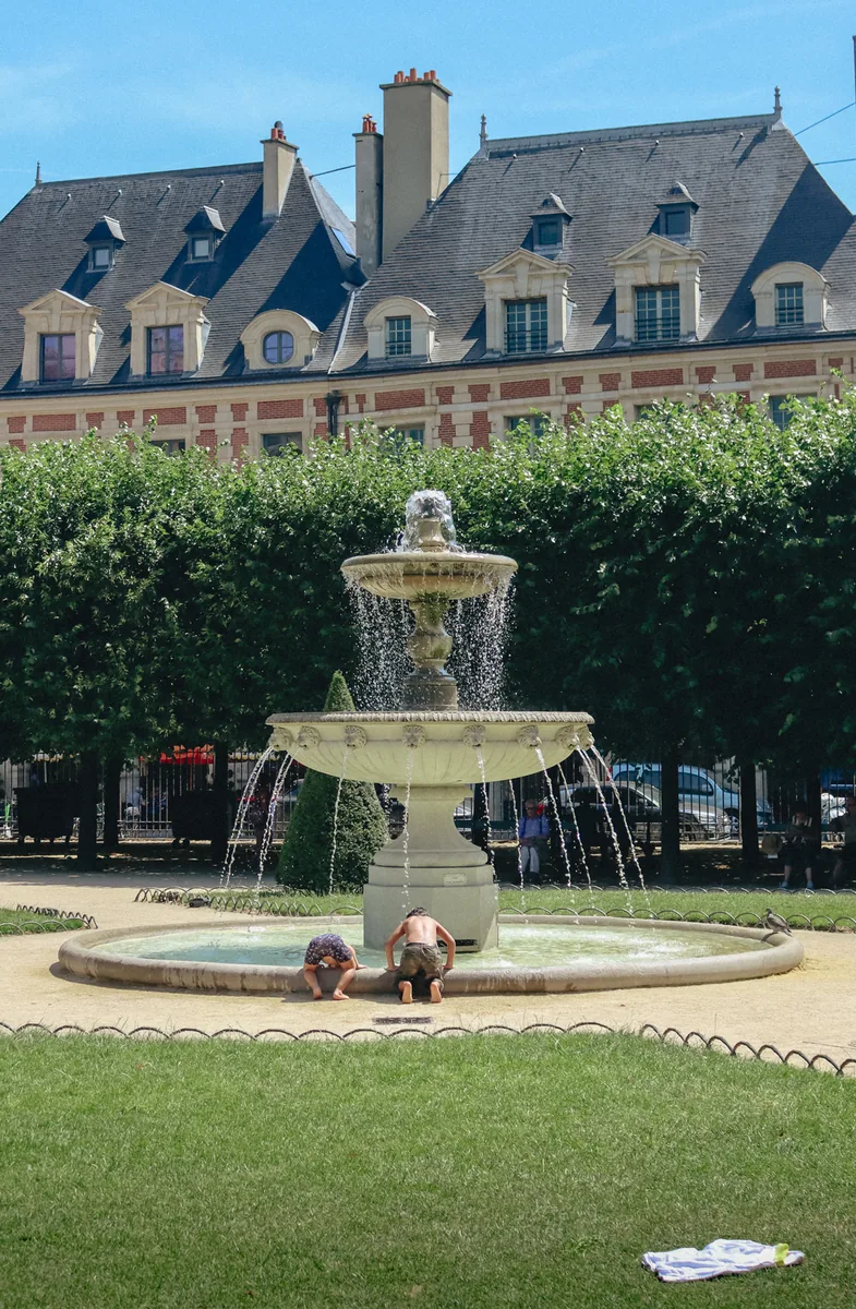 A fountain playing on the lawn of the Place des Vosges, Paris.