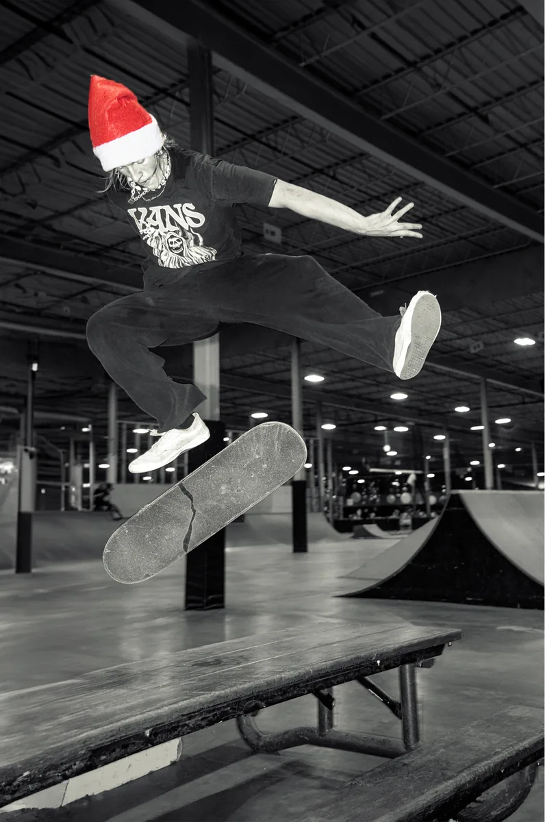 A skater in a Santa hat mid-ollie over a rail, in black and white.