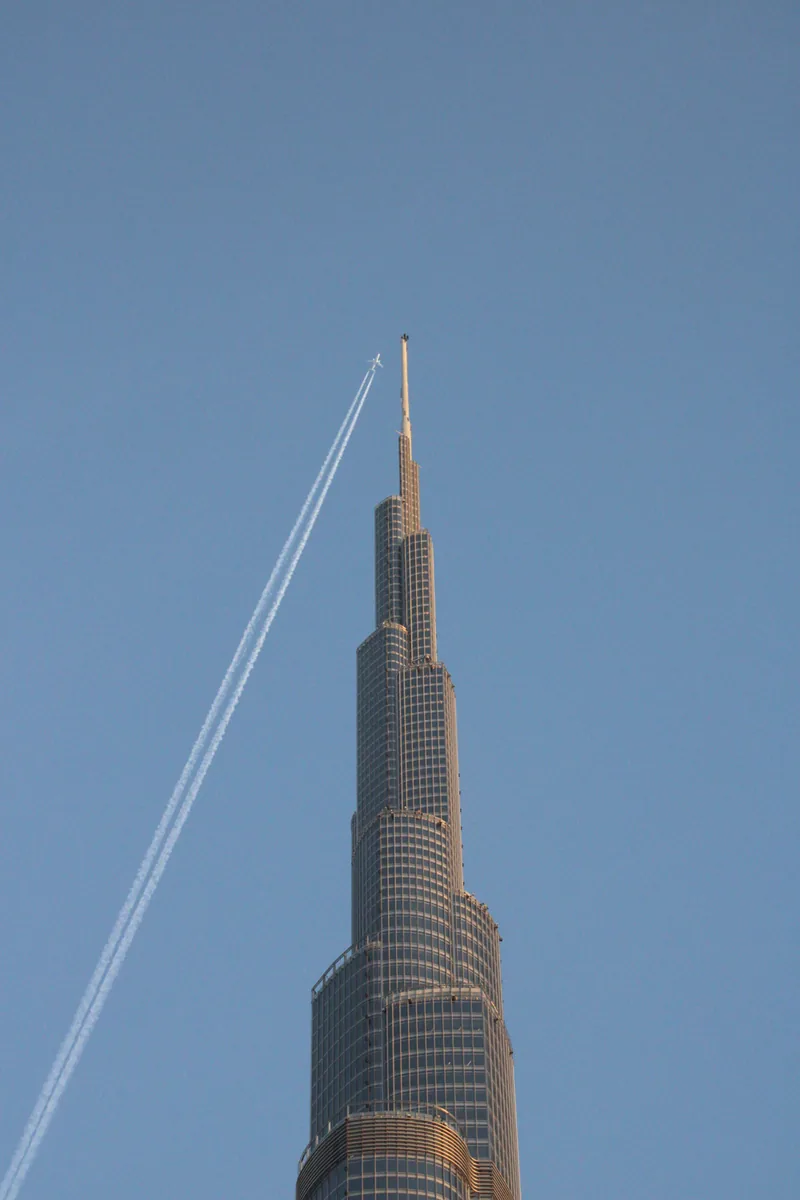 The spire of the Burj Khalifa, Dubai, crossed by a jet contrail.