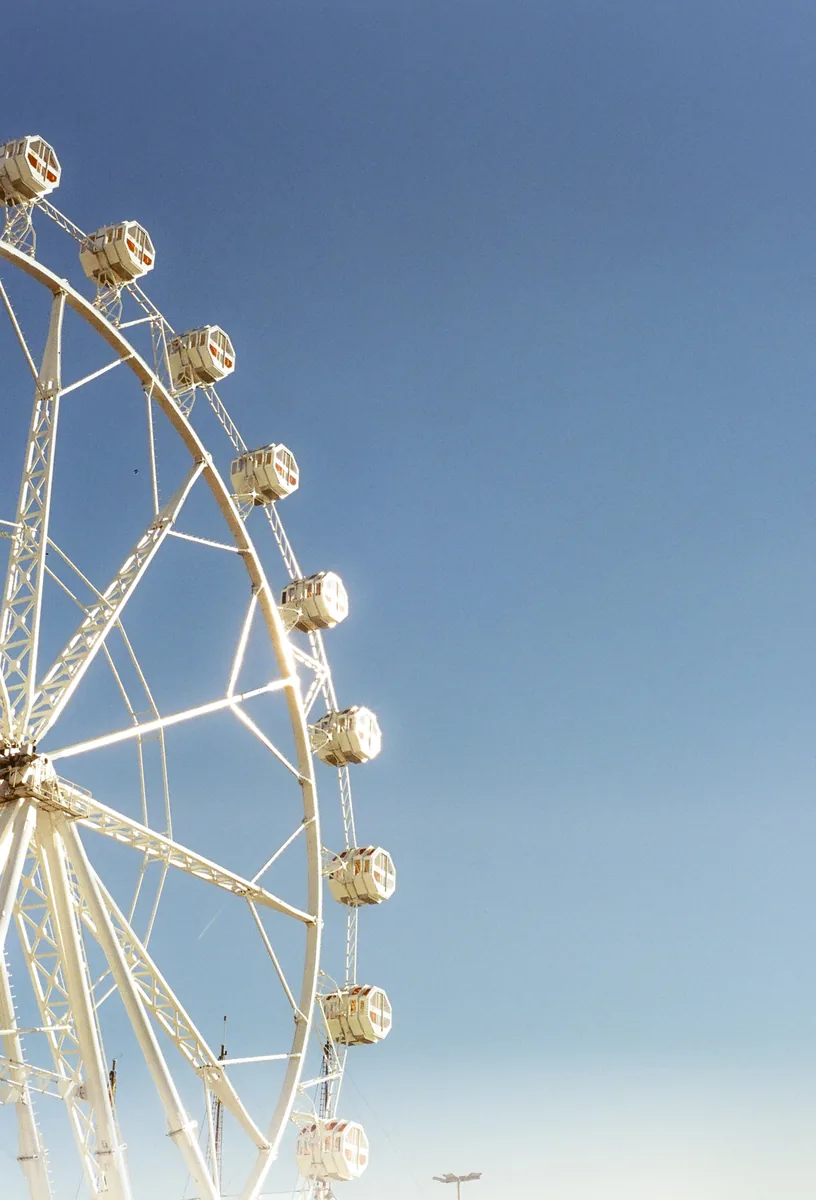 Half an observation wheel, its cabins catching low sun against a clear sky.