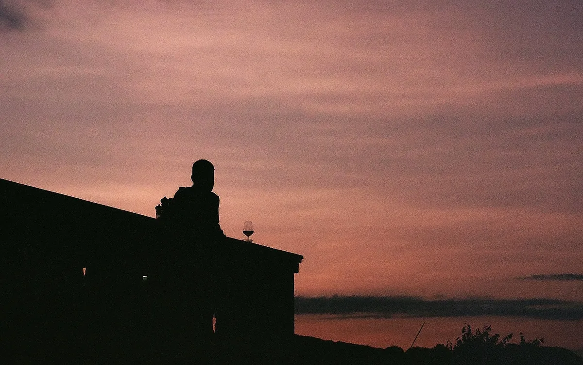 A chapel roofline in silhouette against a pink dusk sky.