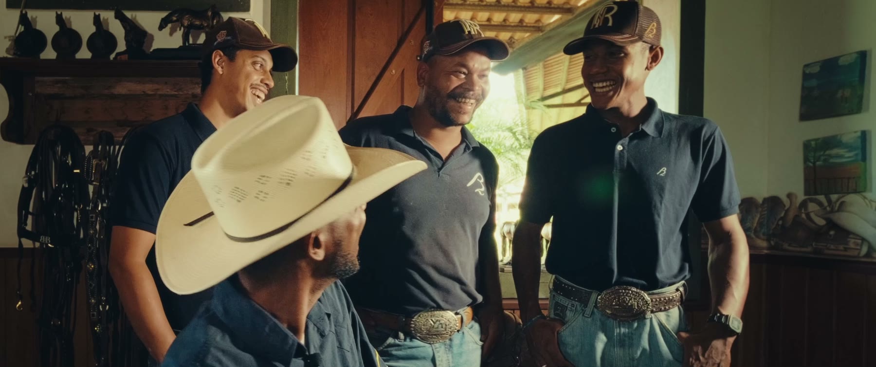 Still from the B2B Ranch film: four ranch hands standing together in a tack room.